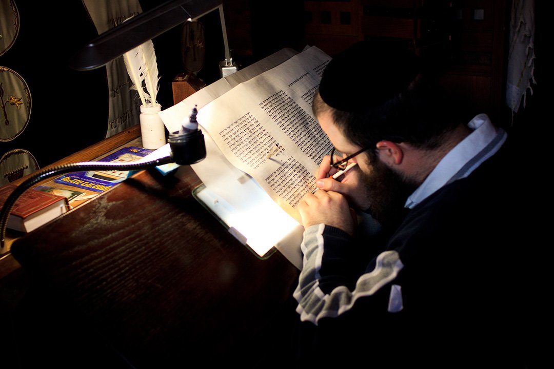 Человек переписывает свитки Торы на горе Масада в Израиле