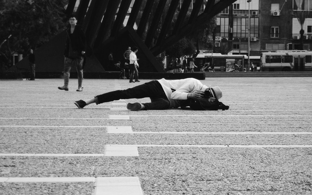 Фотограф Саша Морозов лежит на земле на площади Тель-Авива