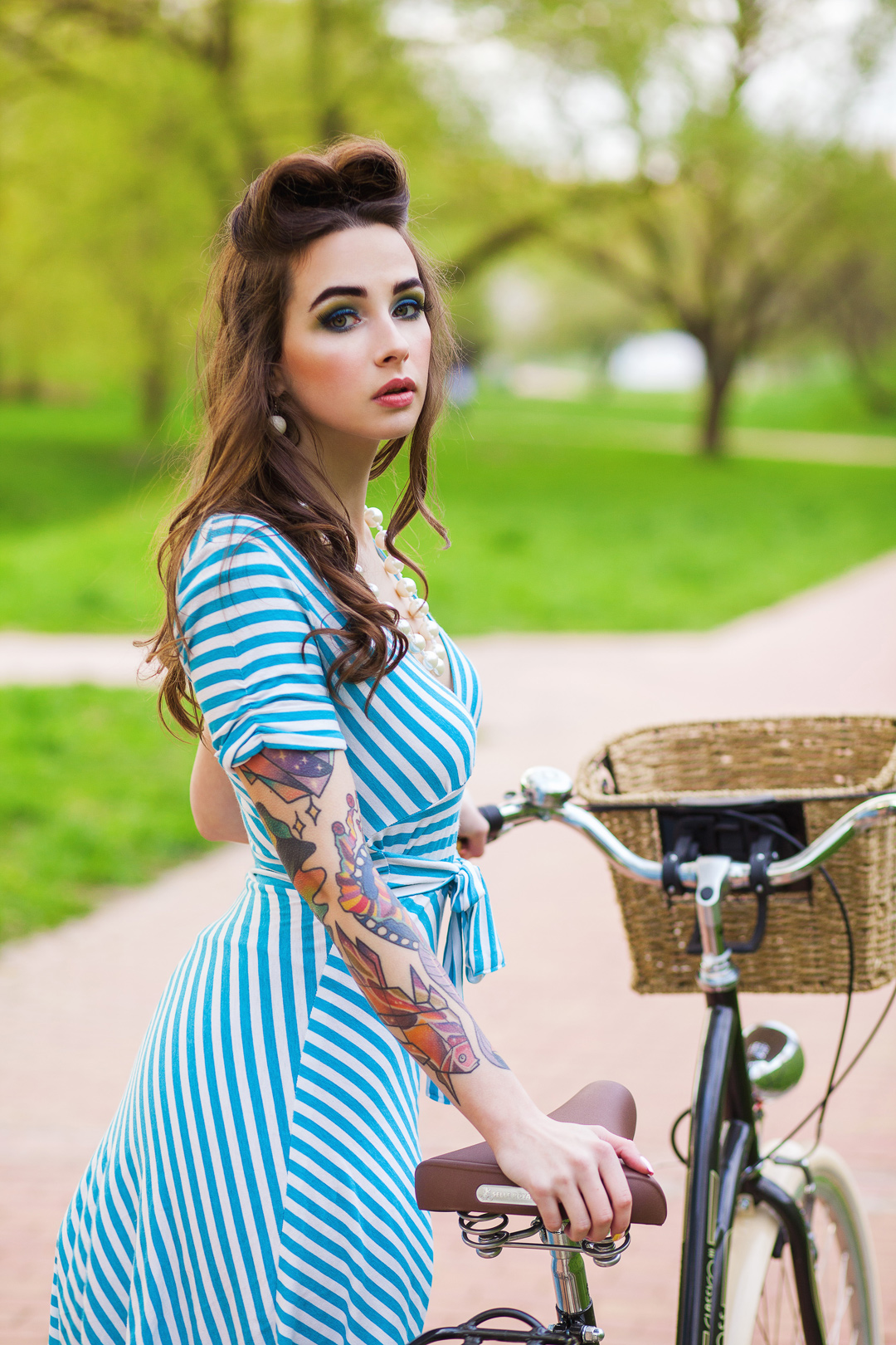 Татуированная модель Дарья Дамилола с велосипедом в парке